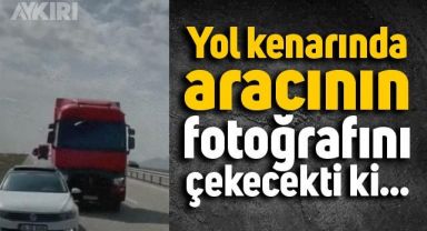 Yol kenarında aracının fotoğrafını çekmek isteyen adam