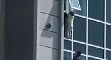 Yürekleri ağza getiren anlar! Binanın camından düşmek üzere olan bir çocuk, son anda kurtuldu